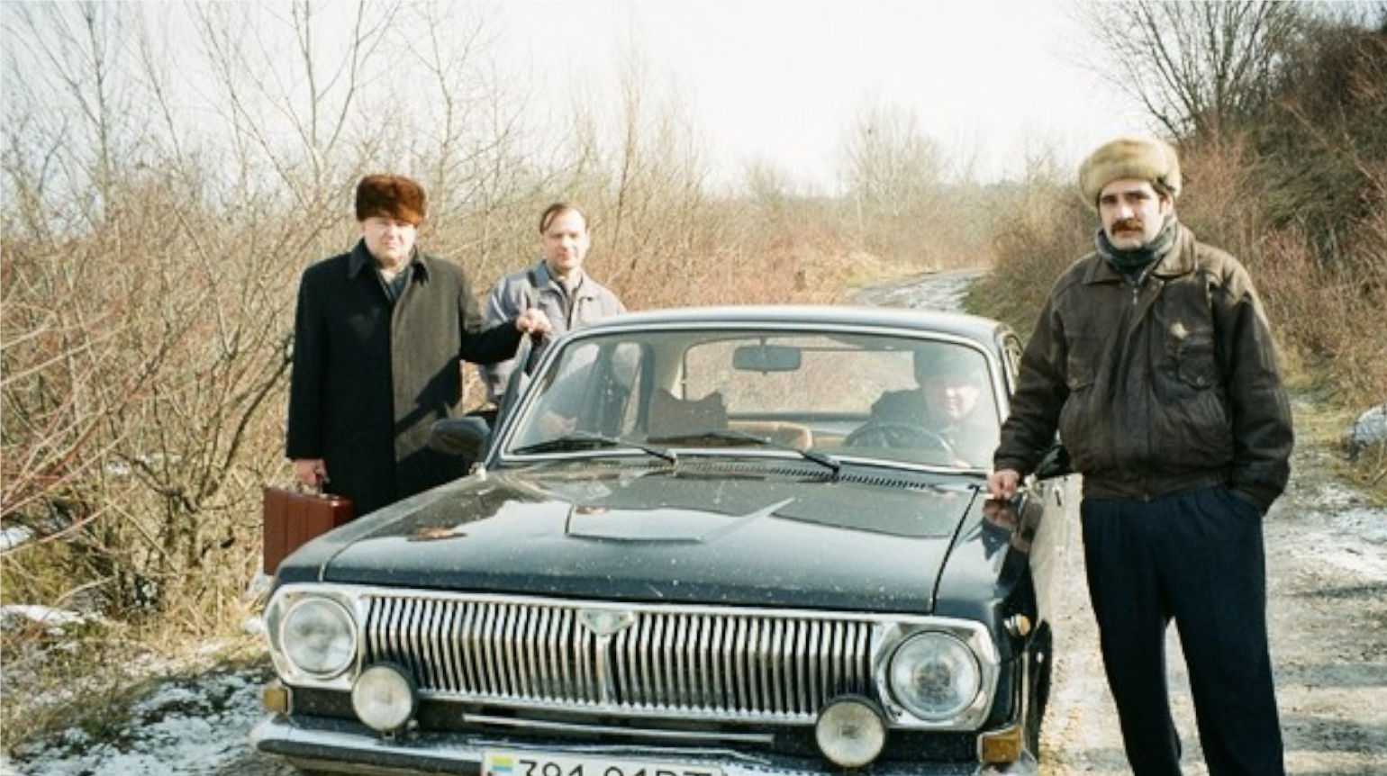 Tre uomini in Ucraina in posa per una foto davanti a un'auto