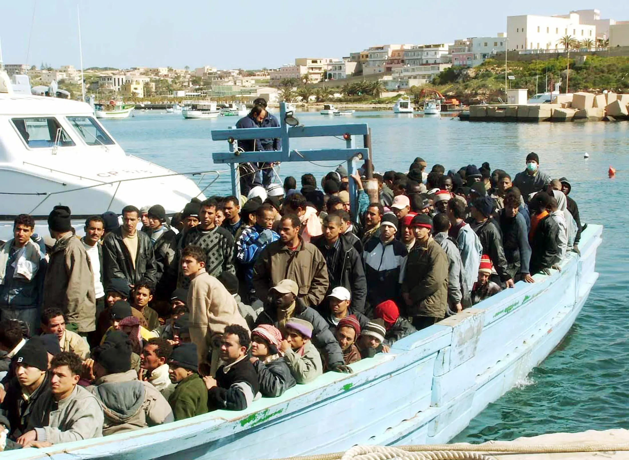 Lampedusa, nuovo barcone approda in porto, mentre riprende il carico delle bare